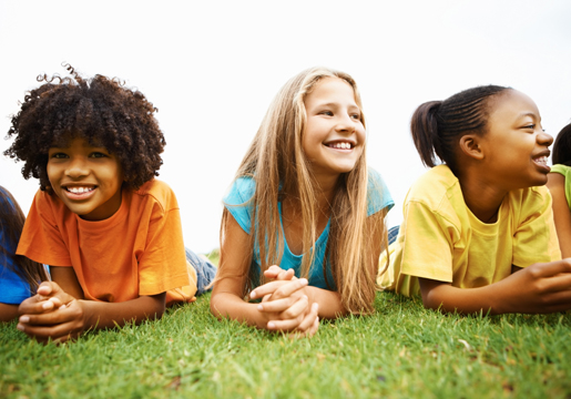 Three kids laying in grass