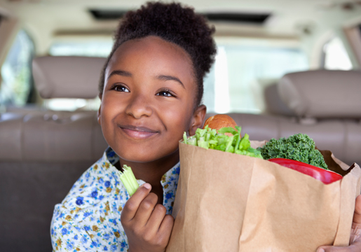 Girl in car eats celery from grocery bag