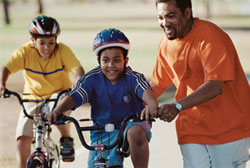 parent helping child ride bicycle